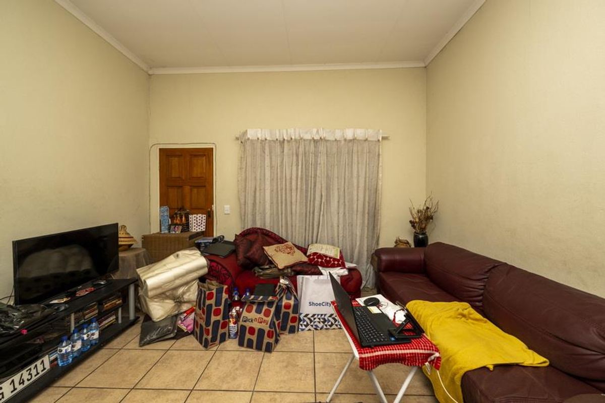 A living room space featuring tiled flooring and a wooden door, providing a functional area for relaxation.