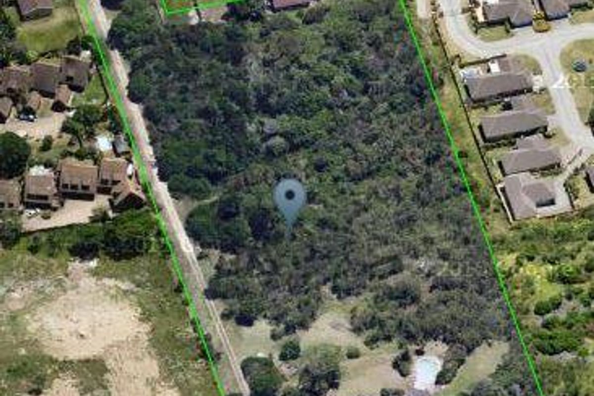 An aerial view of a large residential plot featuring dense vegetation and an existing swimming pool area.