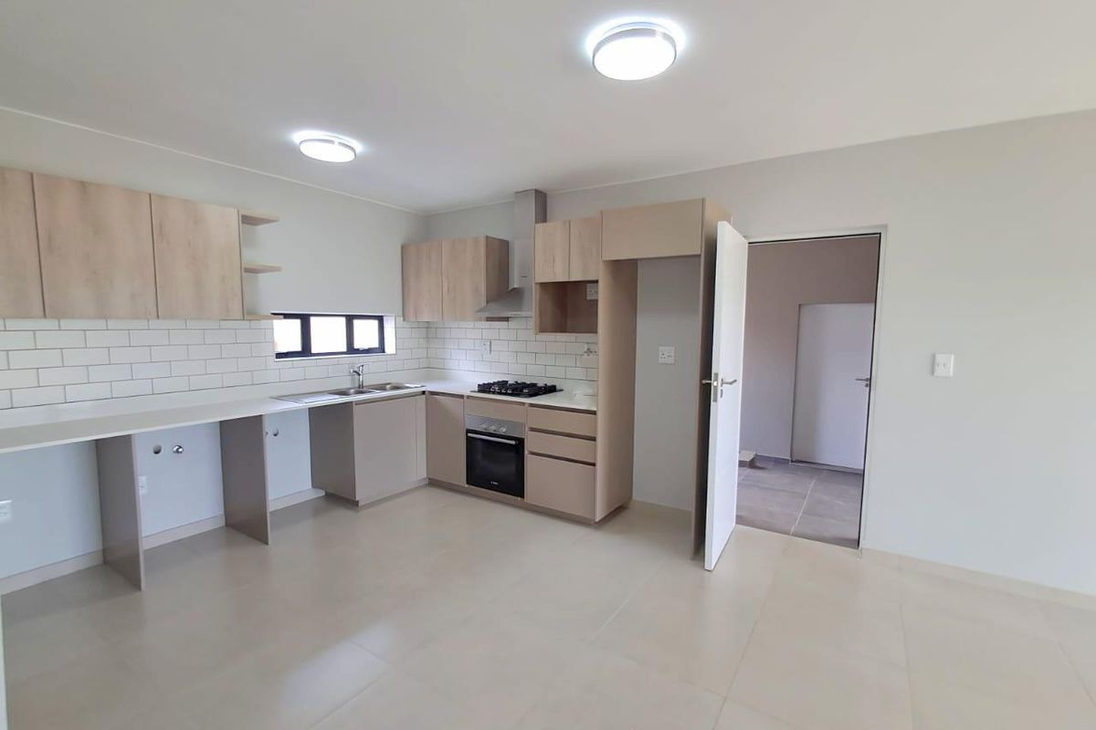 Modern kitchen featuring light wood cabinetry, subway tile backsplash, built-in oven, gas hob, and extractor fan, with tiled flooring throughout.