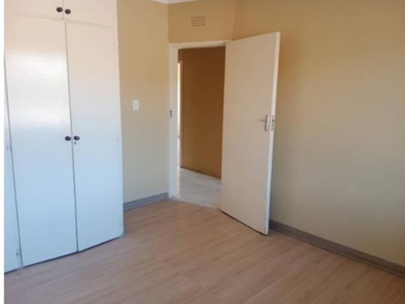 An empty bedroom featuring light-toned laminate flooring and built-in storage cupboards, offering a clean and neutral space ready for personalization.