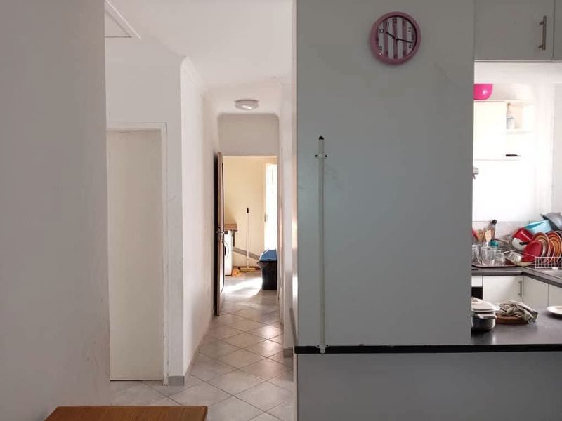 A view from the kitchen looking into a tiled hallway leading towards a rear utility area.