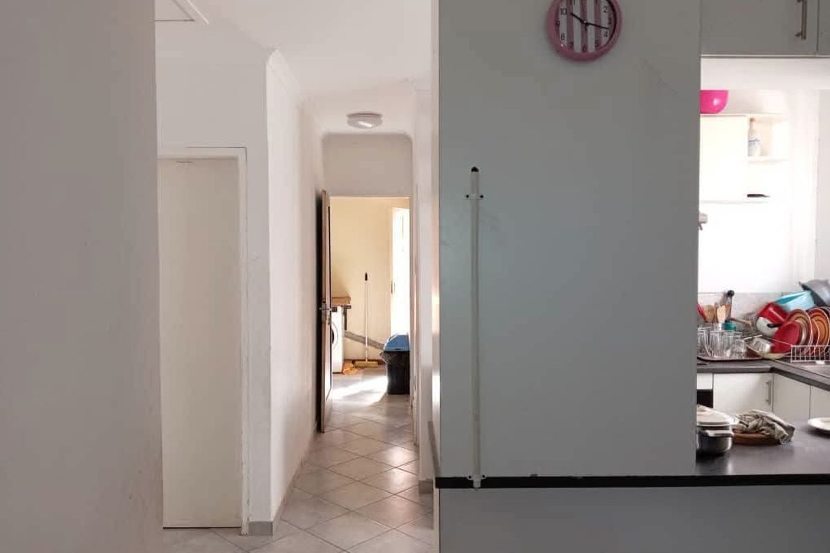 A view from the kitchen looking into a tiled hallway leading towards a rear utility area.