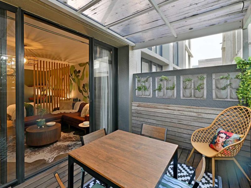 A covered balcony featuring timber decking, wall cladding, and vertical planters, providing a seamless transition from the interior living space.
