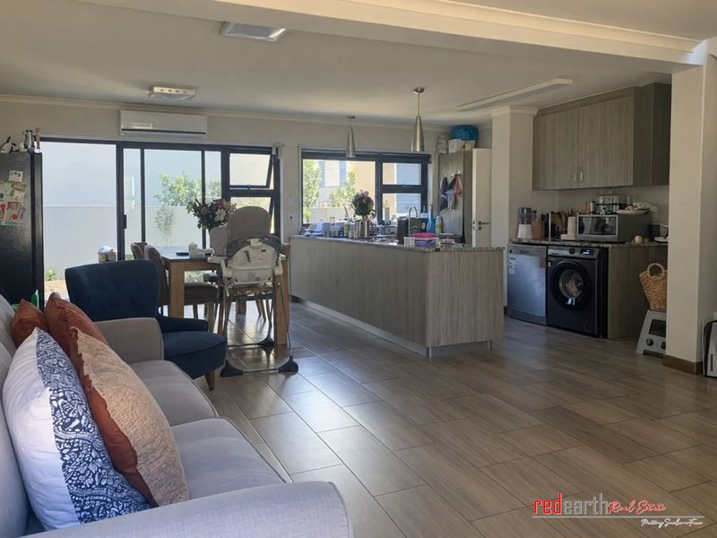 Spacious open-plan living and kitchen area featuring modern cabinetry, stone countertops, tiled flooring, and large sliding doors leading to the outdoor space.