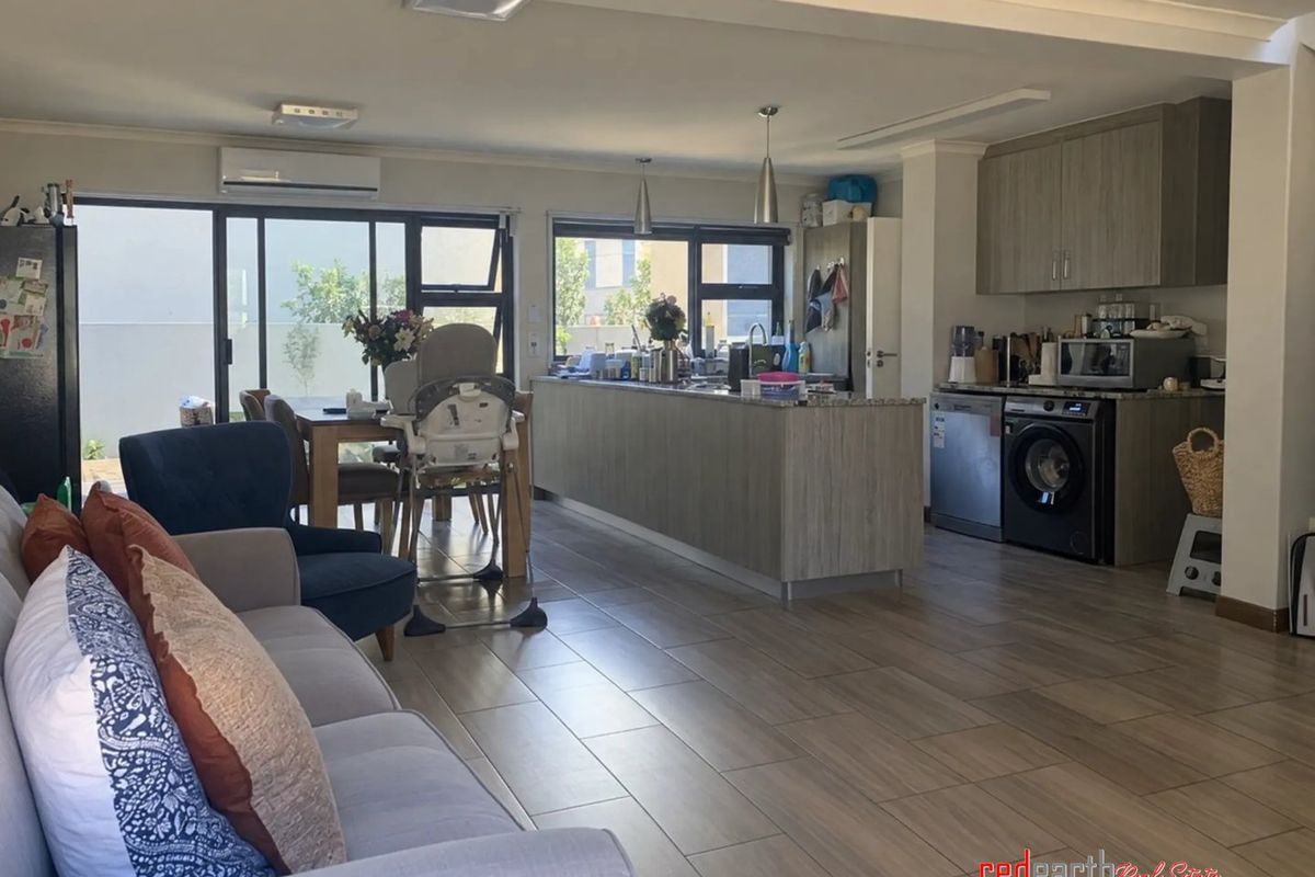 Spacious open-plan living and kitchen area featuring modern cabinetry, stone countertops, tiled flooring, and large sliding doors leading to the outdoor space.