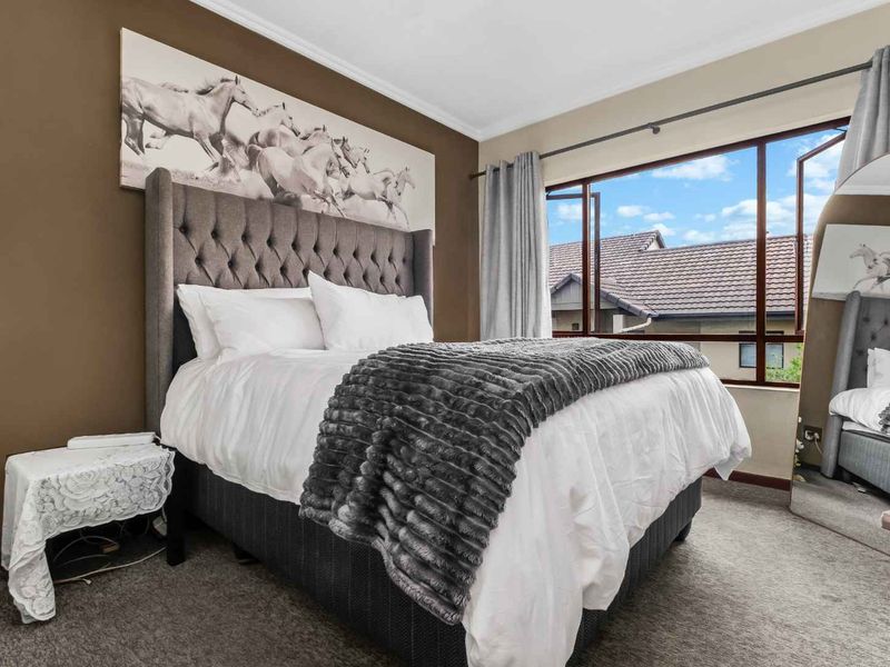 A well-maintained bedroom featuring carpeted flooring and a large casement window that allows for natural light.