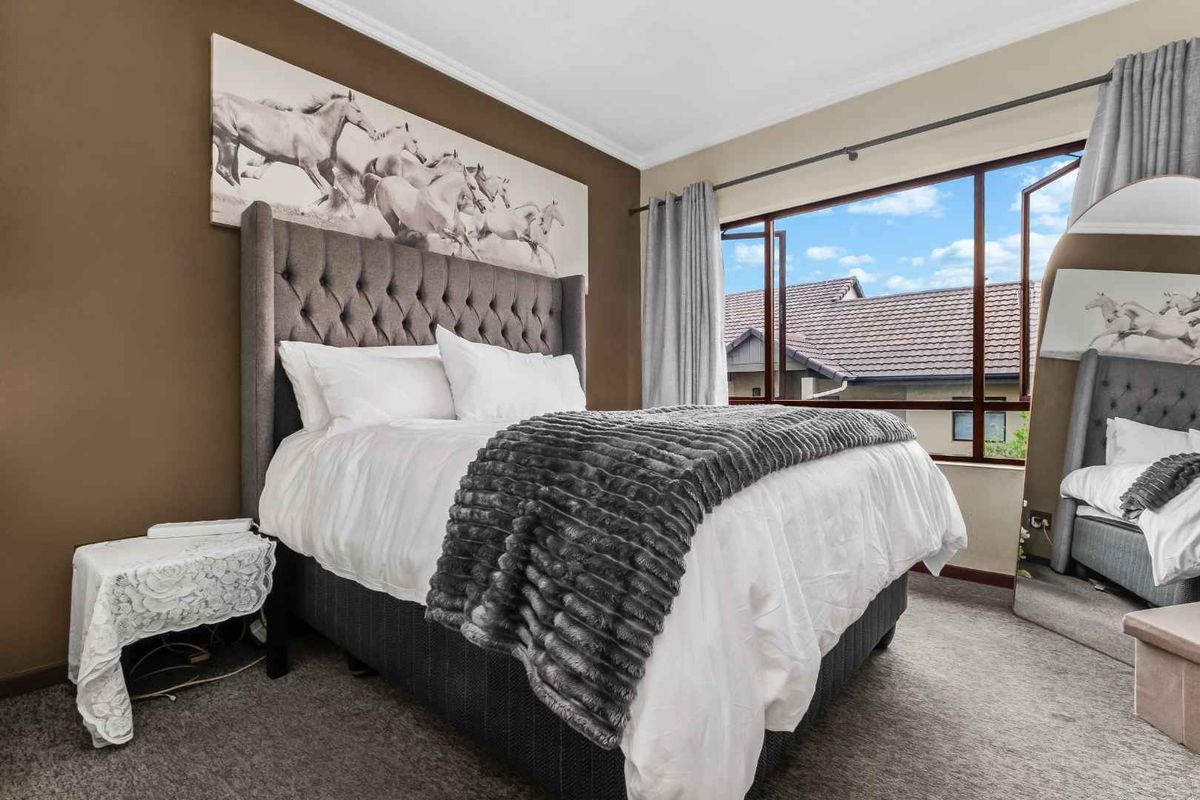 A well-maintained bedroom featuring carpeted flooring and a large casement window that allows for natural light.