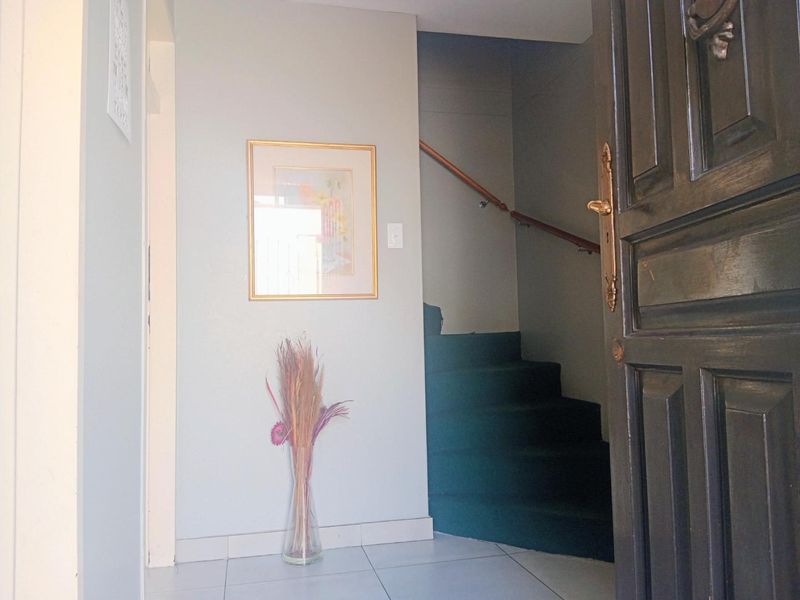 Entrance foyer featuring tiled flooring and a staircase with a timber handrail, leading to the upper level of the townhouse.