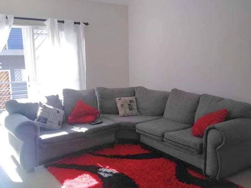 A bright living room featuring neutral tiled flooring and a sliding glass door providing access to the exterior.