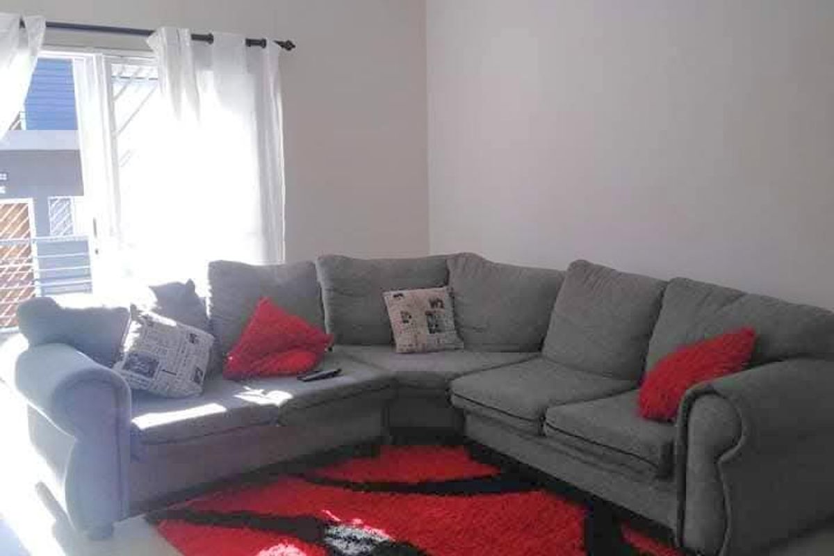 A bright living room featuring neutral tiled flooring and a sliding glass door providing access to the exterior.