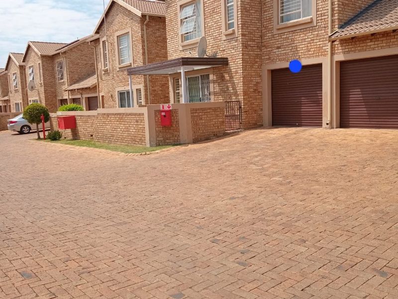 A well-maintained face brick apartment complex featuring paved driveways, secure roller garage doors, and classic architectural detailing.