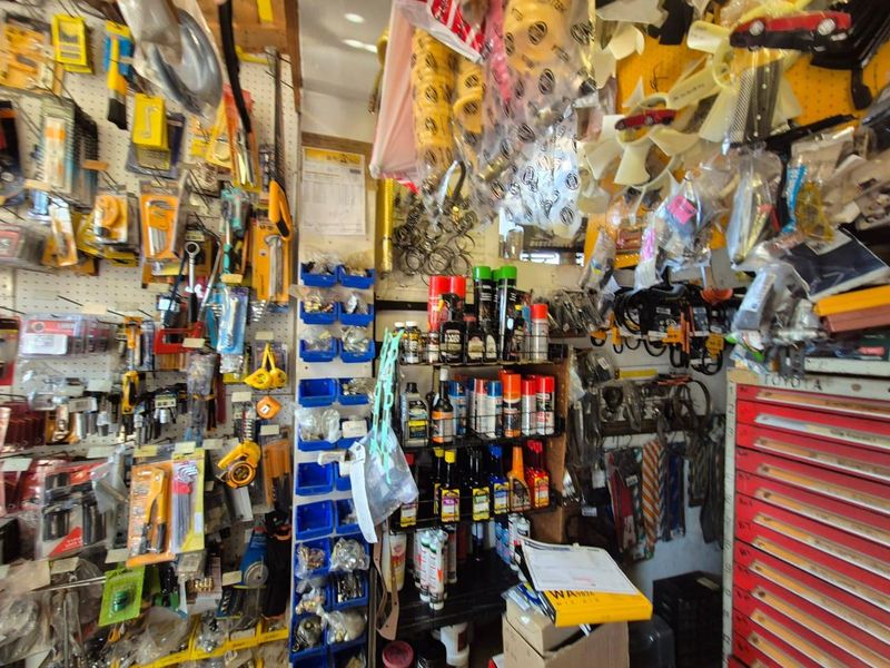 A cluttered utility or workshop space featuring extensive wall-mounted pegboard storage, industrial shelving, and metal storage cabinets for tools and automotive parts.