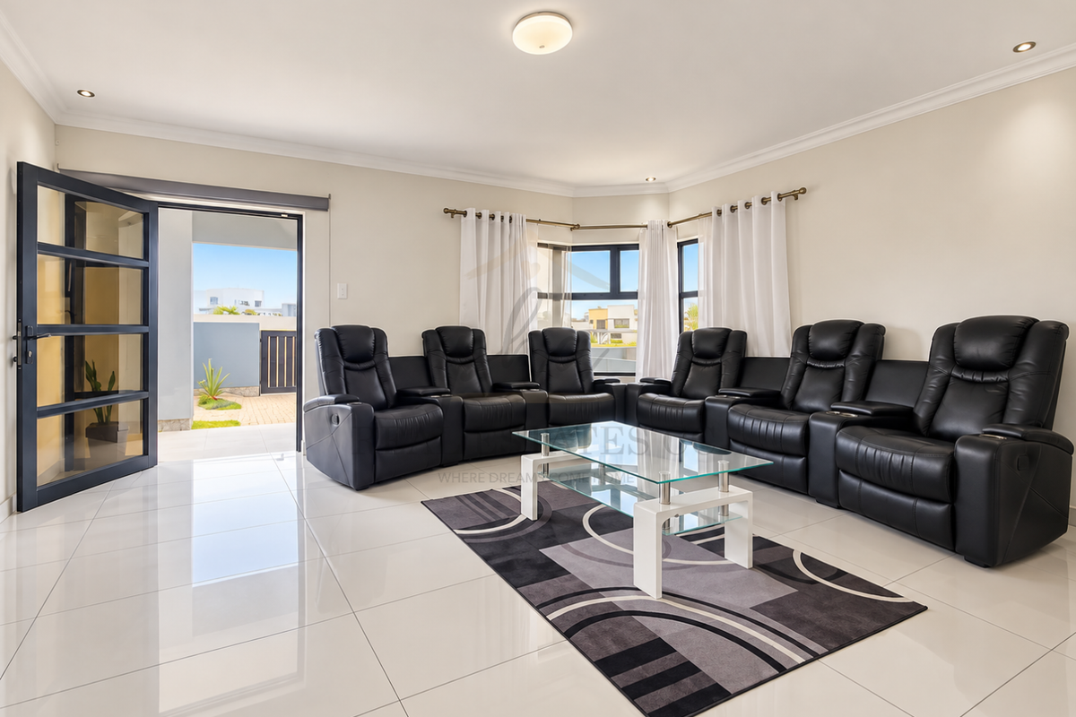 Spacious living room featuring polished porcelain tile flooring, recessed lighting, and large aluminium-framed windows providing access to an outdoor patio area.