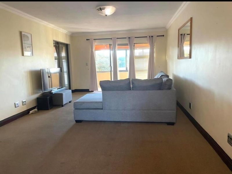 A spacious living room featuring carpet flooring, cove molding, and large sliding glass doors that provide access to an outdoor balcony area.