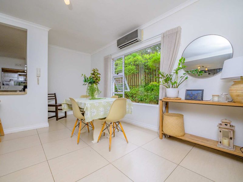 Bright dining area featuring tiled flooring, a split-system air conditioner, and a convenient pass-through window connecting to the kitchen.