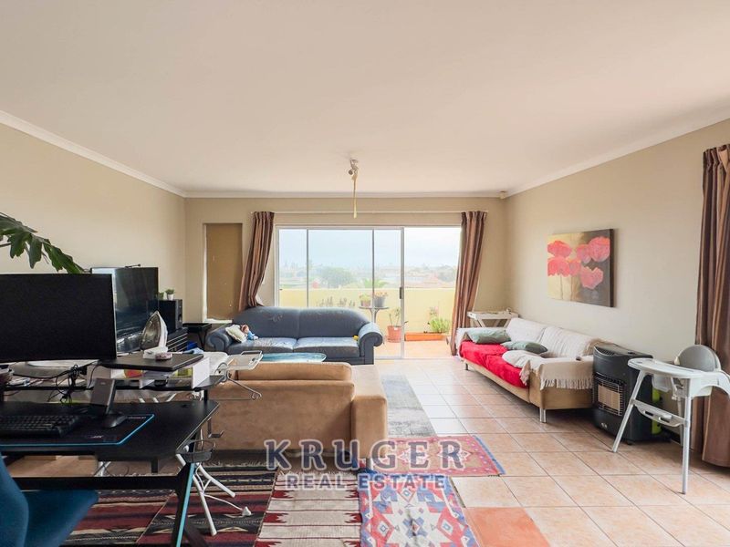 Spacious living area featuring tiled flooring and large sliding glass doors that provide access to an outdoor balcony.