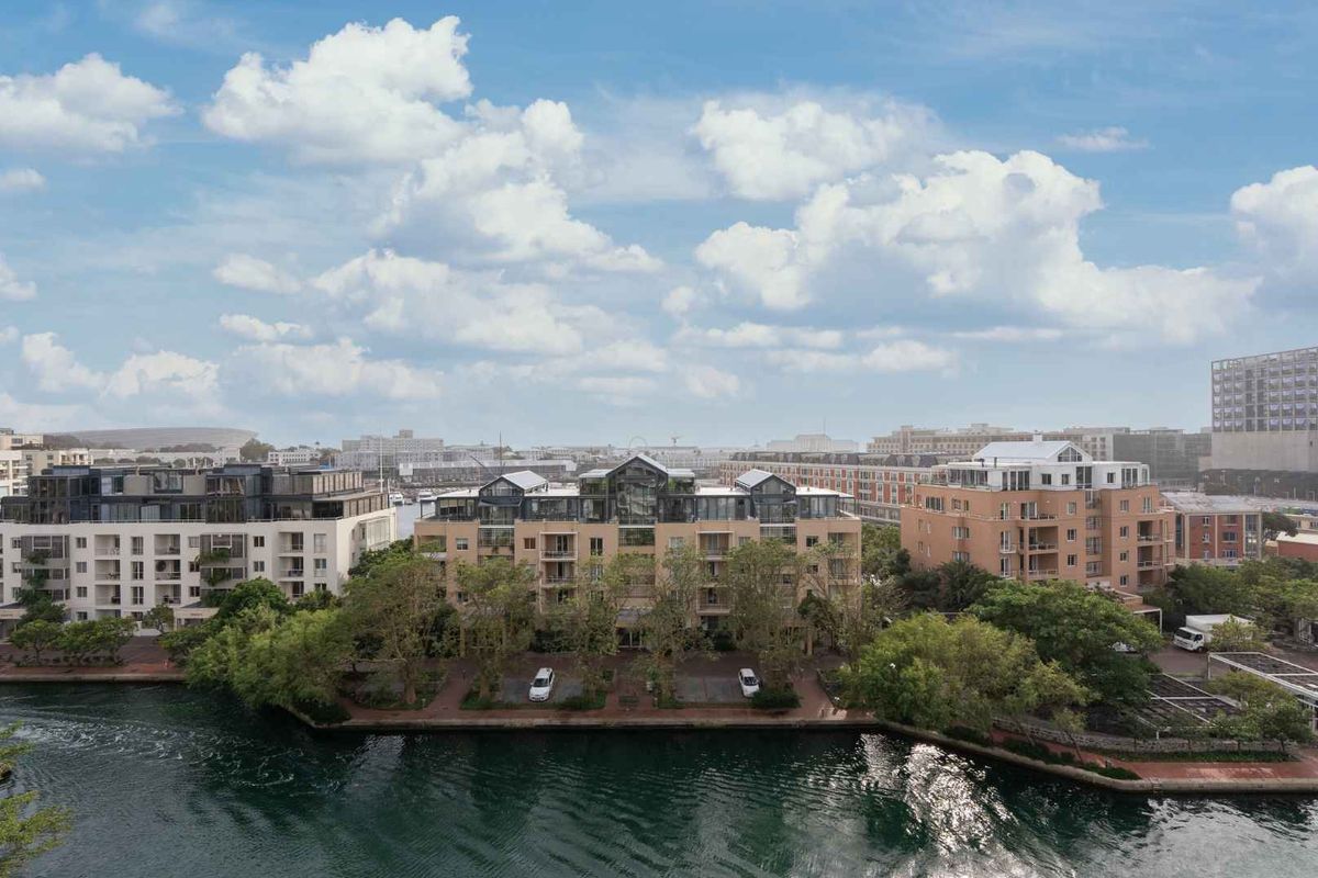 Aerial view of a waterfront apartment complex featuring landscaped grounds and surrounding urban infrastructure.