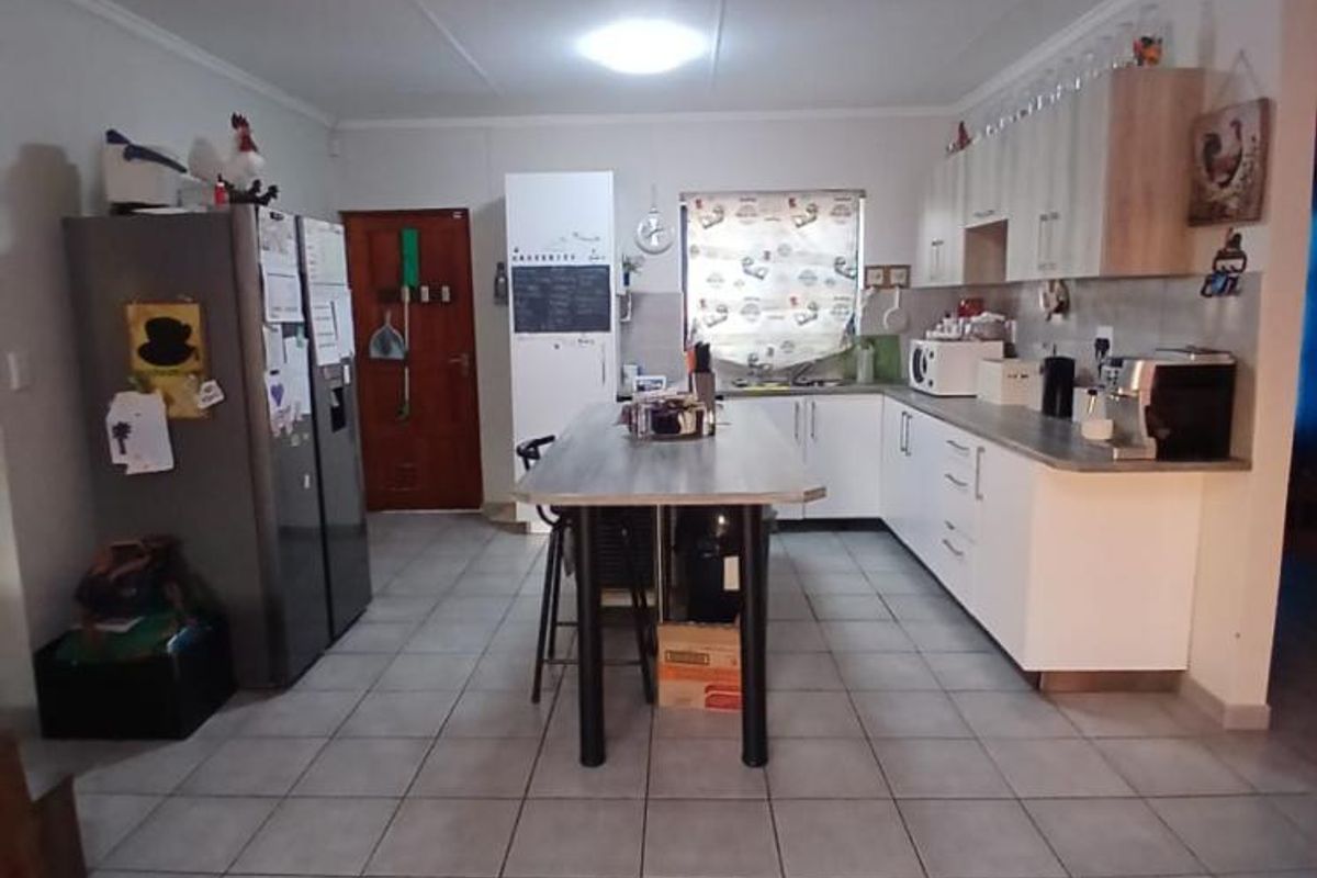 A functional kitchen featuring white cabinetry, a central island, and tiled flooring, providing a practical workspace with ample storage.