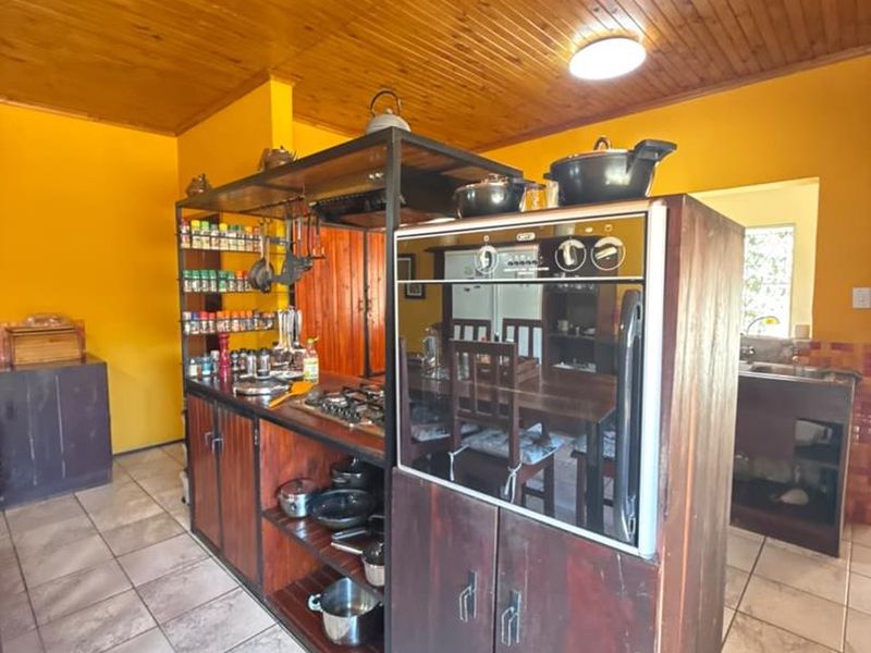 A kitchen featuring a central island with a built-in oven and gas hob, complemented by timber ceiling paneling and tiled flooring.