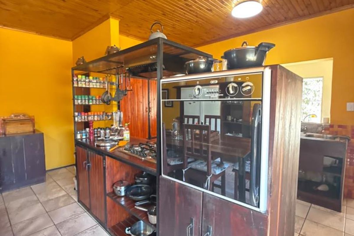 A kitchen featuring a central island with a built-in oven and gas hob, complemented by timber ceiling paneling and tiled flooring.