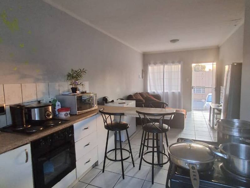 Open-plan kitchen and living area featuring tiled flooring, built-in cabinetry, and a breakfast counter, leading to an exterior access point.