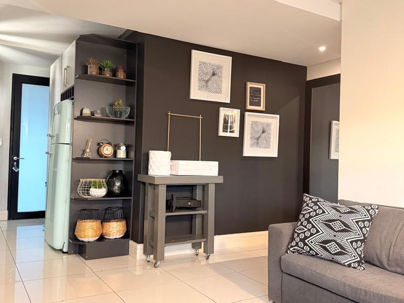 Modern open-plan living area featuring sleek tiled flooring, a dark accent wall with built-in shelving, and recessed lighting.