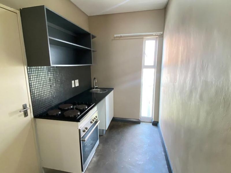 A compact, functional kitchen featuring built-in cabinetry, an electric oven and hob, a sink, and a tiled backsplash.