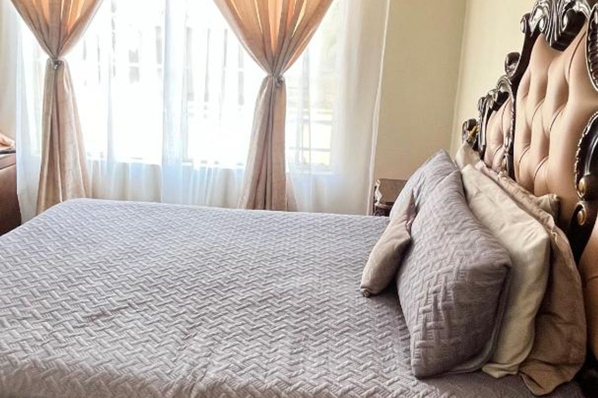 A bedroom featuring tiled flooring and a window with curtains, providing a functional and comfortable sleeping space.