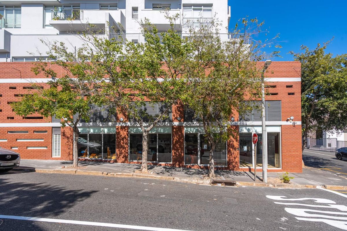 Street-level retail storefront featuring a classic red brick facade and large display windows, situated in a well-maintained urban building.