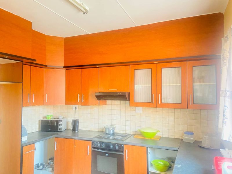 A functional kitchen featuring wood-tone cabinetry, tiled backsplash, and integrated cooking appliances, offering a dated aesthetic ready for modernization.