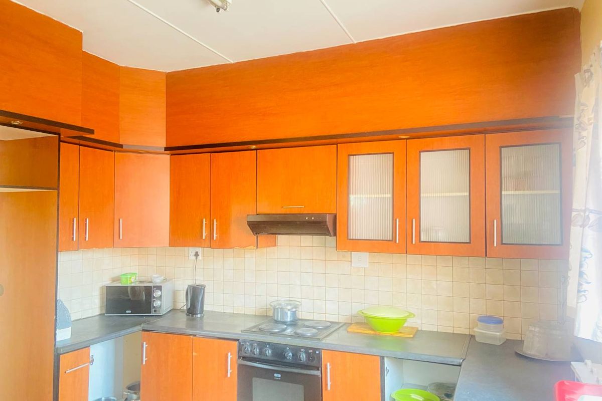 A functional kitchen featuring wood-tone cabinetry, tiled backsplash, and integrated cooking appliances, offering a dated aesthetic ready for modernization.