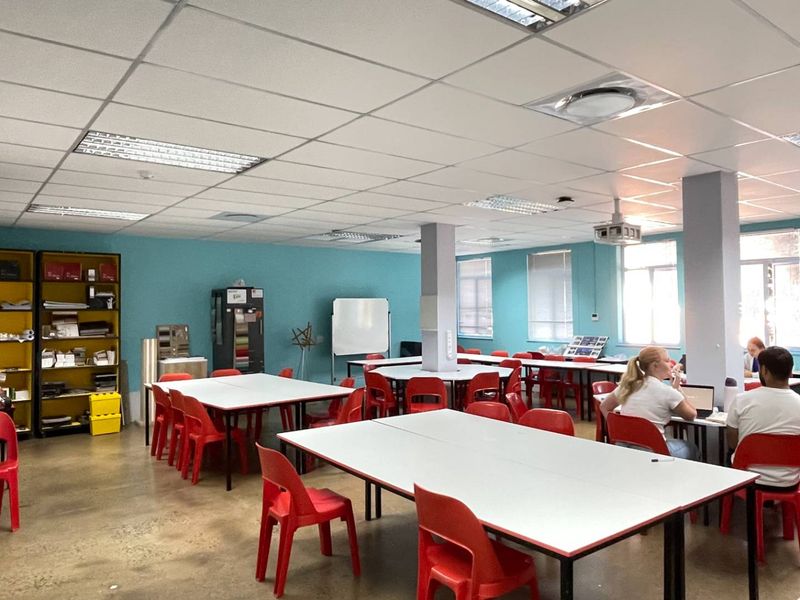 Spacious open-plan office area featuring a suspended ceiling, recessed lighting, structural columns, and built-in storage shelving.
