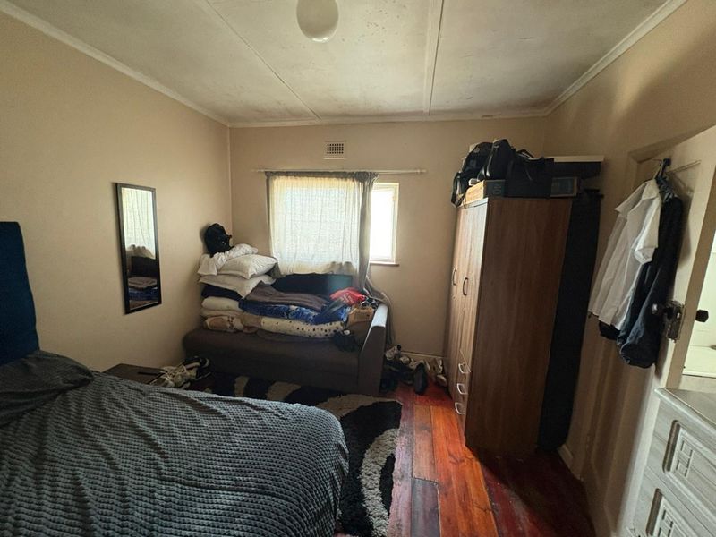 A bedroom featuring timber flooring and a ceiling vent, requiring cosmetic updates to improve the overall condition and appeal of the space.