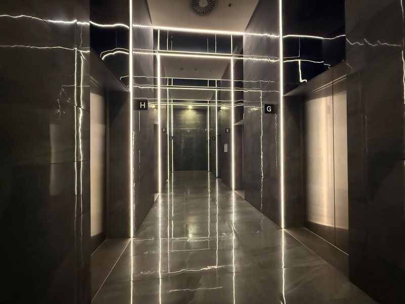 Modern office building elevator lobby featuring polished stone finishes and integrated vertical LED strip lighting.
