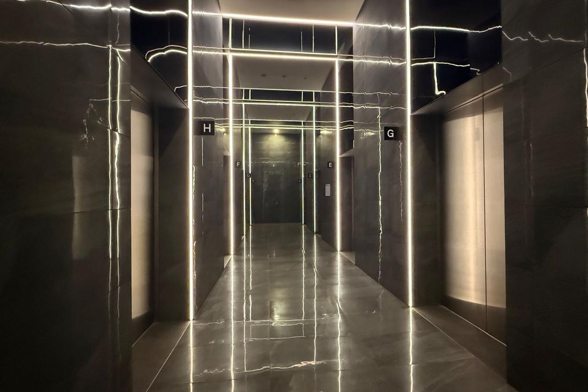 Modern office building elevator lobby featuring polished stone finishes and integrated vertical LED strip lighting.