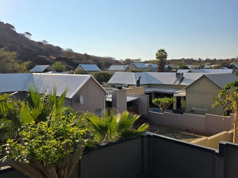 Elevated view overlooking a residential neighborhood with metal-roofed houses and surrounding landscape.