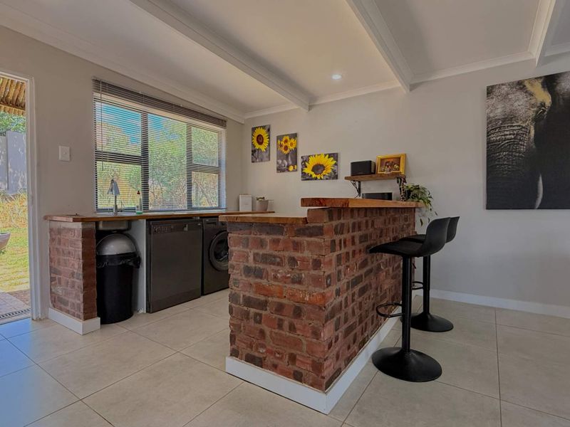 A functional scullery area featuring an exposed brick breakfast bar, timber countertops, tiled flooring, and direct access to the outdoor patio.