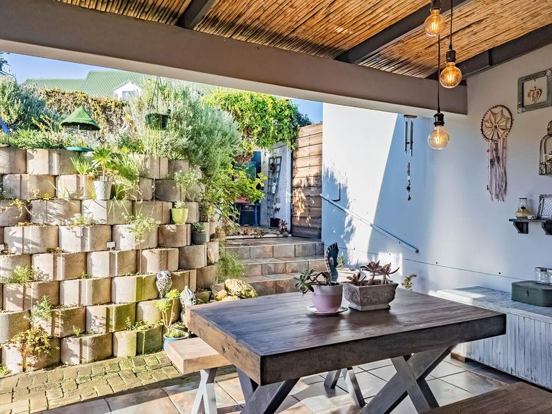 Covered patio area featuring a bamboo ceiling, tiled flooring, and a tiered concrete block retaining wall with integrated garden planting.