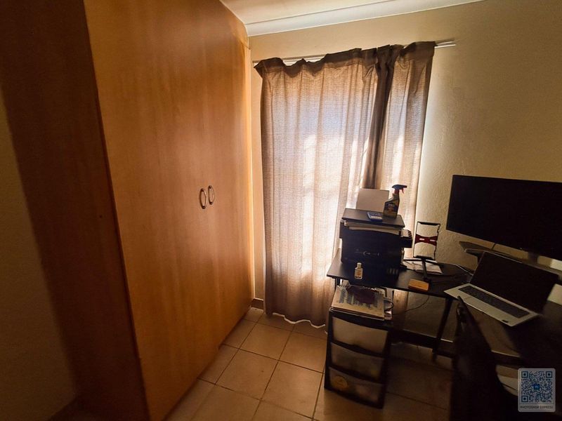 A bedroom featuring tiled flooring and a built-in wooden wardrobe, providing functional storage space.