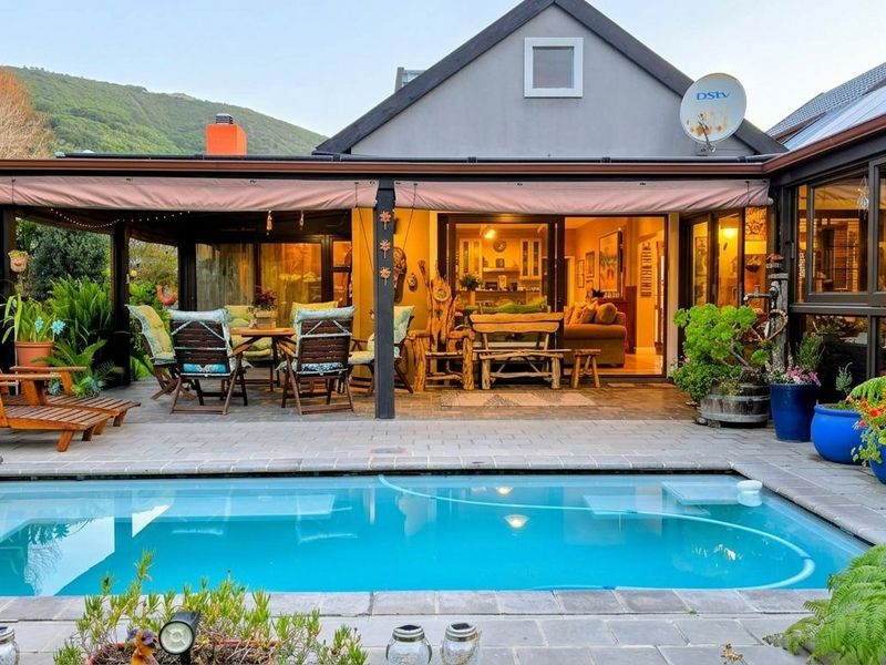 A well-maintained outdoor entertainment area featuring a swimming pool, paved deck, and a covered patio with direct access to the home's interior.