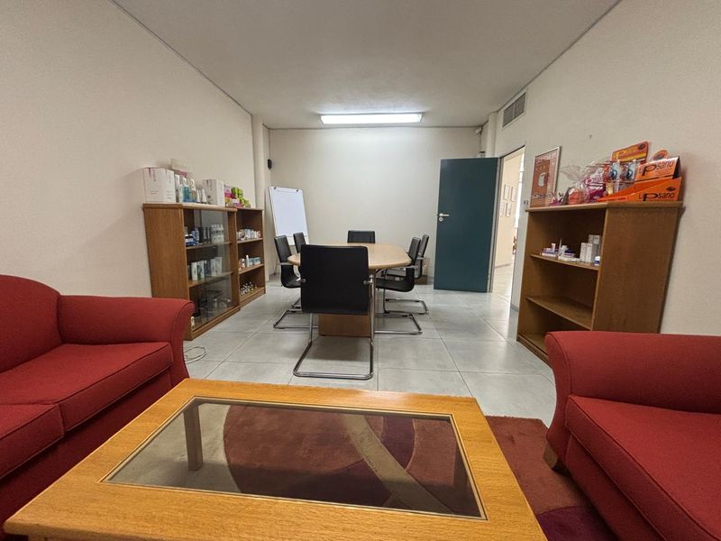 A functional office space featuring tiled flooring, overhead fluorescent lighting, and integrated air conditioning ventilation, suitable for a professional meeting or consultation area.