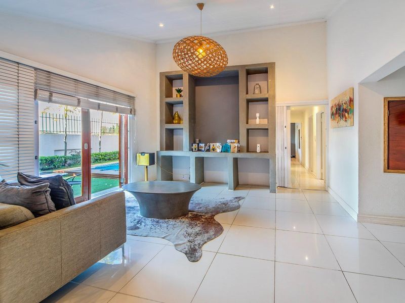 Spacious living room featuring large sliding glass doors, modern tiled flooring, and a prominent built-in concrete shelving unit.