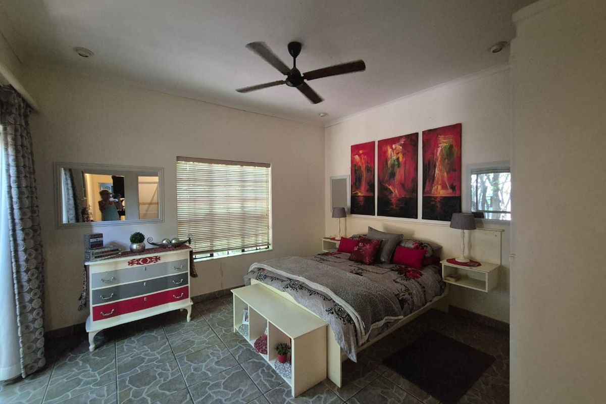 Spacious bedroom featuring tiled flooring, a ceiling fan, and built-in bedside shelving units.