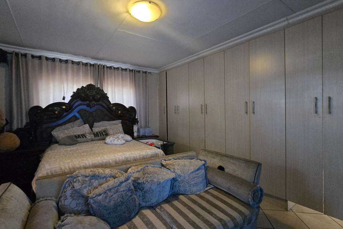 Spacious bedroom featuring extensive built-in cupboards, tiled flooring, and a central ceiling light fixture.