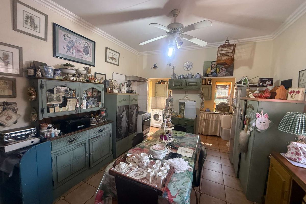 A functional kitchen area featuring tiled flooring, ceiling fan, and built-in cabinetry, with an adjacent utility space visible in the background.