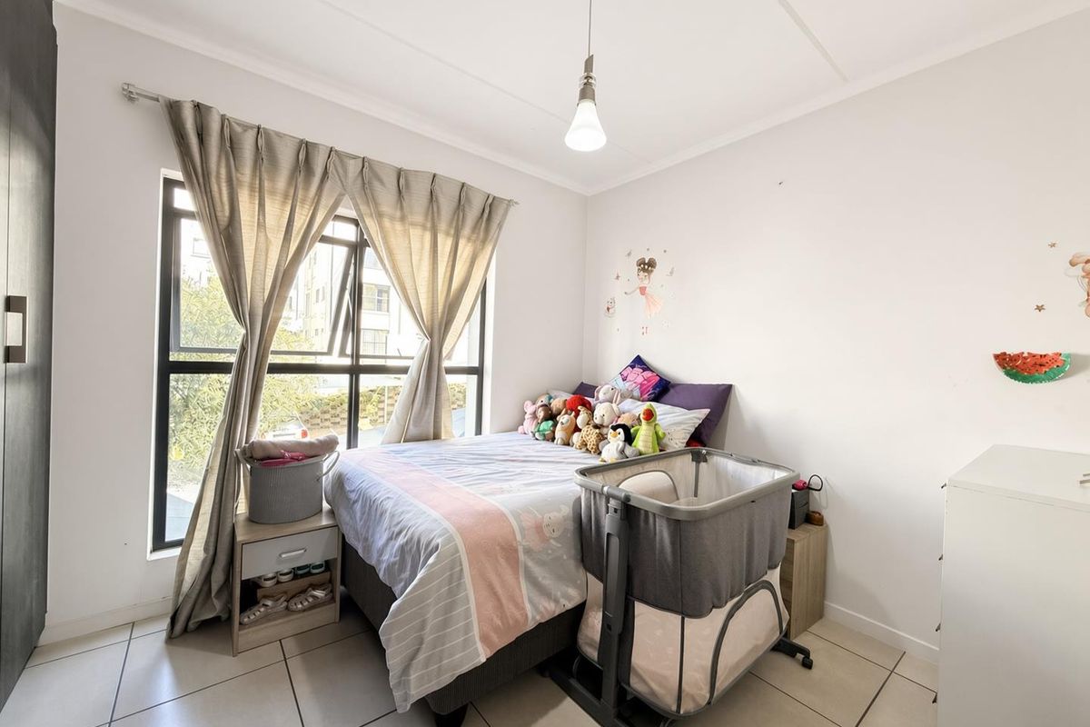 A functional bedroom featuring tiled flooring, a built-in wardrobe, and a large window providing natural light.