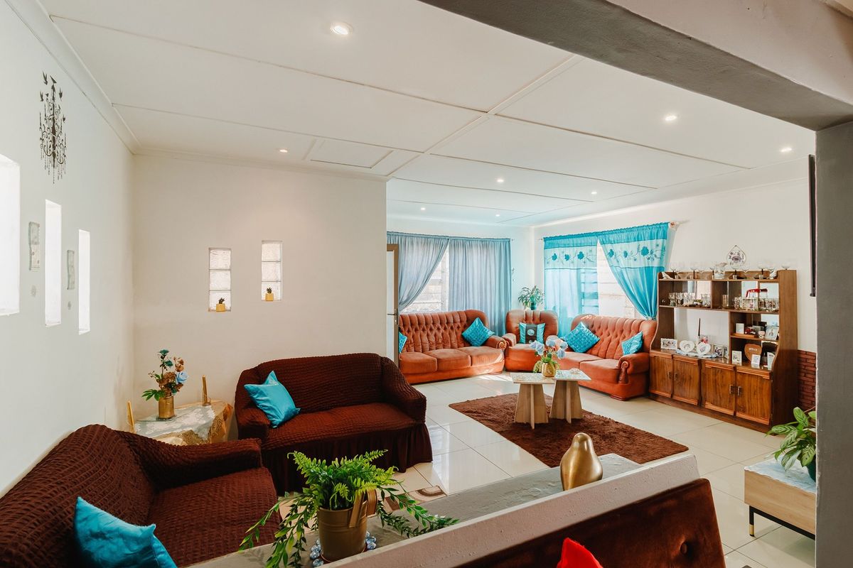 Spacious living area featuring tiled flooring, recessed downlighting, and decorative glass block wall inserts, offering a bright and open layout.