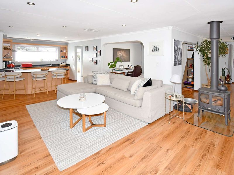 Spacious open-plan living area featuring a modern kitchen with island, laminate flooring, and a cozy wood-burning stove as a central focal point.