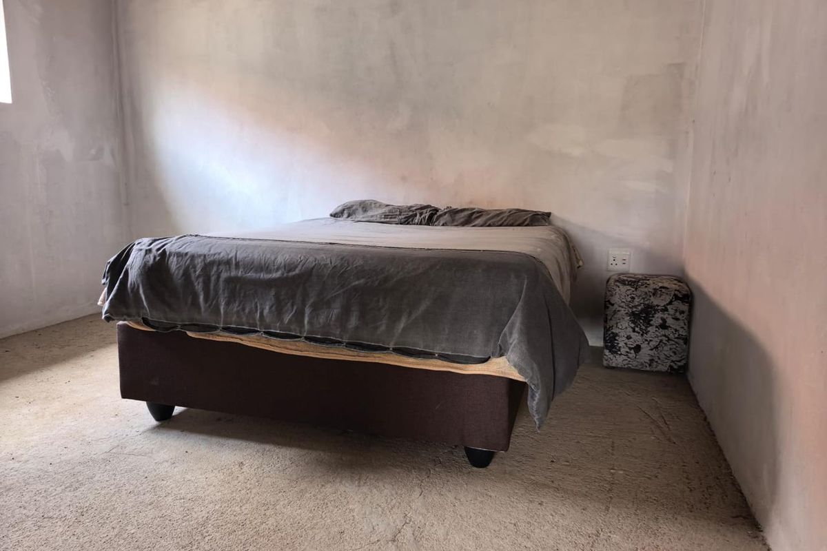 A bedroom featuring unfinished wall surfaces and exposed concrete flooring, presenting a blank canvas for renovation and interior finishing.