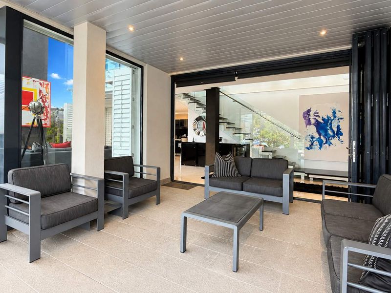 A spacious covered patio featuring tiled flooring, recessed lighting, and large sliding glass doors providing seamless access to the interior living area.